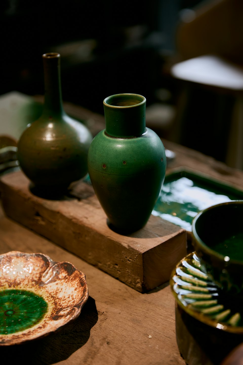 Cerámica artesanal verde expuesta sobre una mesa de madera.
