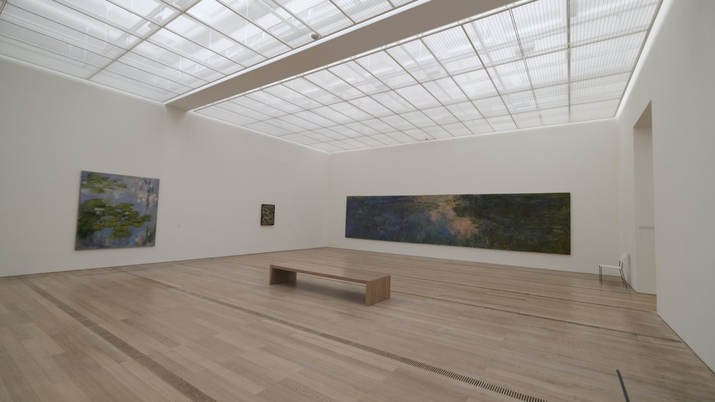 Galería de arte moderno con paredes blancas y cuadros expuestos.