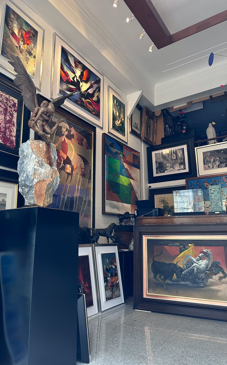 Galería de arte llena de pinturas y una escultura de bronce.
