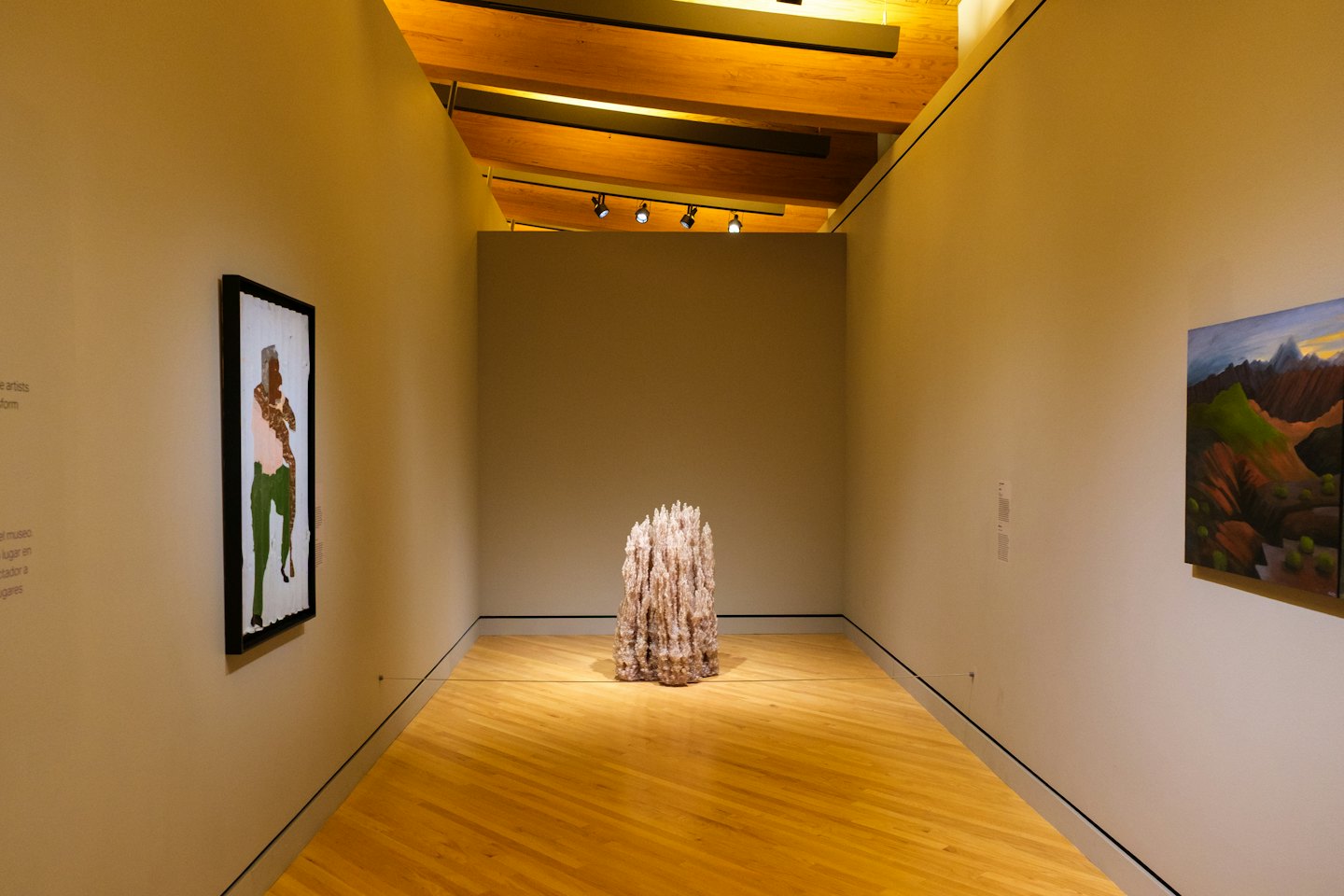 Pasillo de galería de arte con pinturas abstractas y de paisajes.